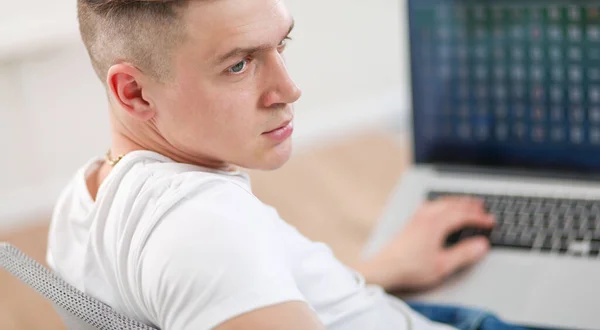 Красивый молодой человек сидит и работает за ноутбуком — стоковое фото