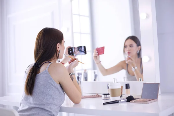 ミラーの前でスマートフォンでメイクアップチュートリアルを撮影美容ブロガー — ストック写真