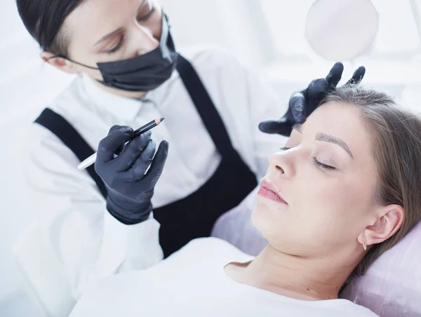 Cosmetologist aplicando a composição permanente nas sobrancelhas — Fotografia de Stock