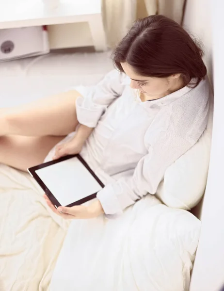 Retrato de mulher usando tablet e beber café enquanto se senta na cama pela manhã — Fotografia de Stock
