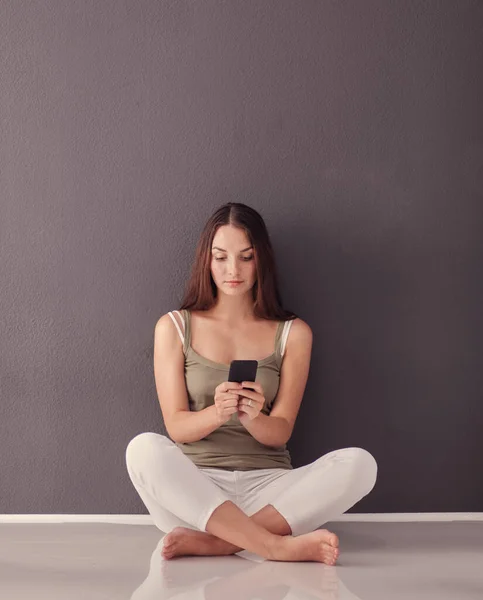 Mujer morena sonriente sentada en el suelo y haciendo selfie en el teléfono inteligente — Foto de Stock