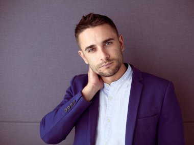 Gri arka planda yalnız oturan genç iş adamı.