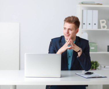 Yakışıklı genç adam dizüstü bilgisayarda oturuyor ve çalışıyor.