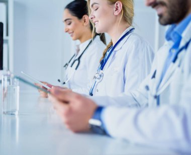 Toplantıdaki doktorlar, masanın üstünde oturuyorlar.