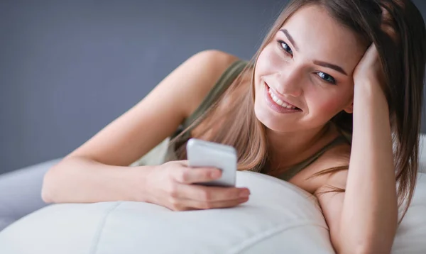 Schöne Frau entspannt sich auf einem weißen Sofa mit einer Tasse Kaffee — Stockfoto