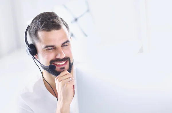 Retrato de un joven con un auricular frente a una computadora portátil — Foto de Stock