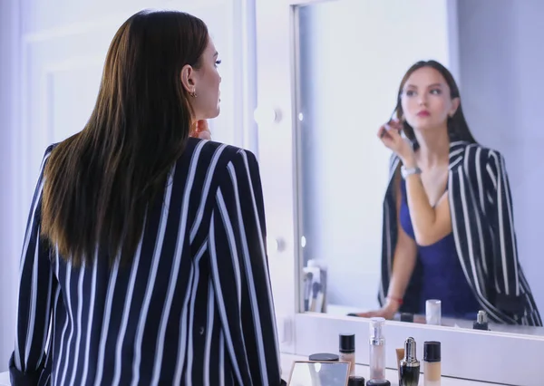 鏡を見ながら化粧をしている若い美女の姿を映し出す — ストック写真
