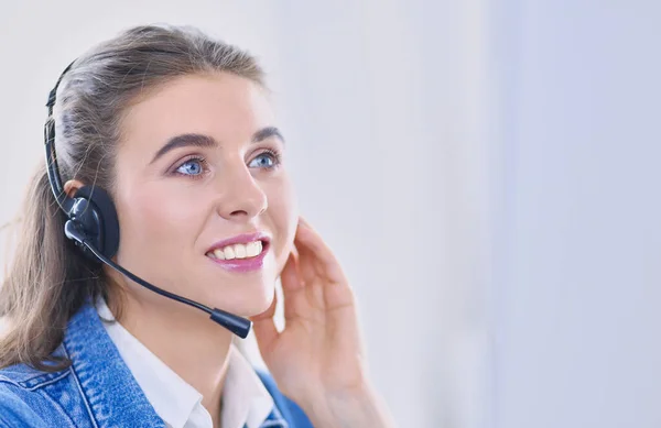 Feliz encantadora joven sentada y trabajando con el ordenador portátil con auriculares en la oficina — Foto de Stock