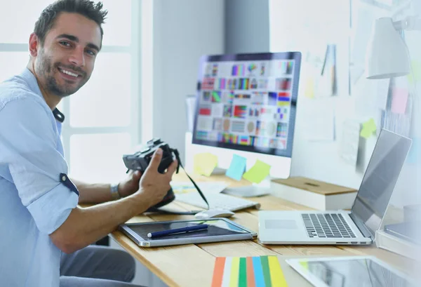 Retrato de jovem designer sentado no estúdio gráfico na frente de laptop e computador enquanto trabalhava online. — Fotografia de Stock