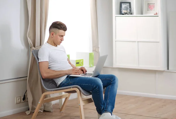 Hezký mladý muž sedí a pracuje na notebooku — Stock fotografie