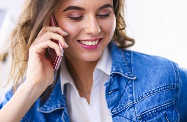 Kafede kahve içip cep telefonuyla konuşan genç bir kadın.