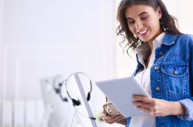 Gülümseyen kadın kahve içiyor ve kafede tablet kullanıyor.