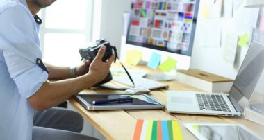 İnternette çalışırken bilgisayarın ve dizüstü bilgisayarın önünde grafik stüdyosunda oturan genç tasarımcının portresi.