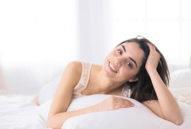 Güzel bir kadın yatağında uzanıyor.
