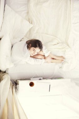 Sabahları yatakta otururken tablet kullanan ve kahve içen kadın portresi