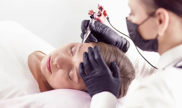 Jonge vrouw ondergaat procedure van wenkbrauw permanente make-up in schoonheidssalon — Stockfoto