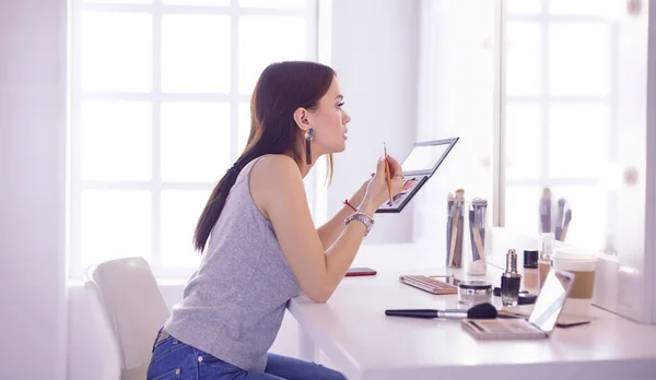 Mujer morena aplicando maquillaje para una cita nocturna frente a un espejo —  Fotos de Stock