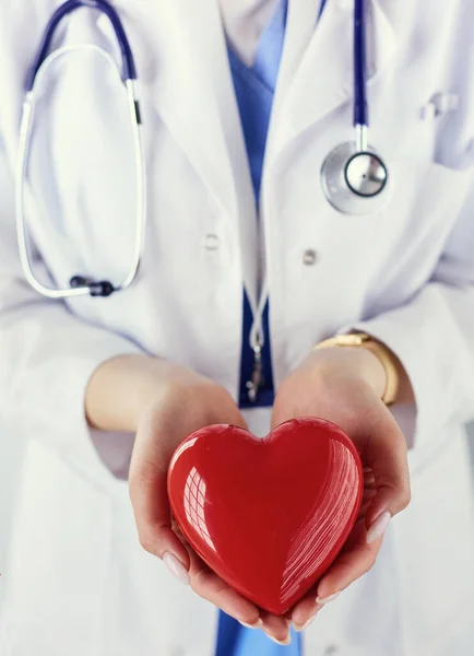 Female doctor with stethoscope holding heart, on light background — Stock Photo, Image