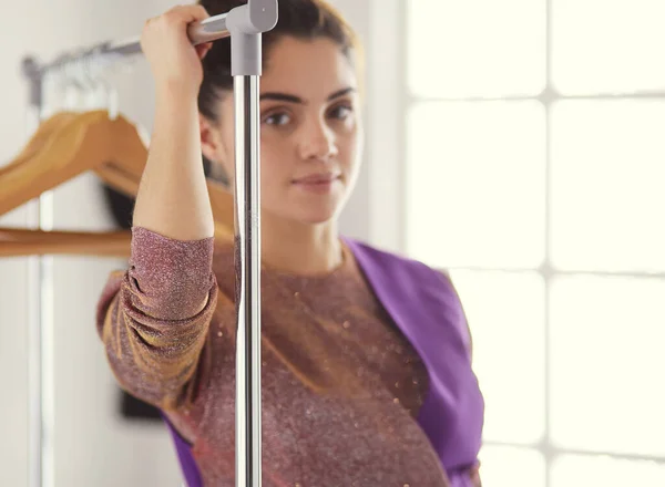 Mooie jonge stylist bij rek met hangers — Stockfoto