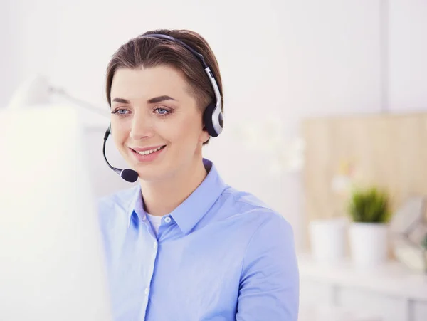 Ernstige mooie jonge vrouw die werkt als support telefoon operator met headset in het kantoor — Stockfoto