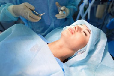 Ameliyat odasında arka planda erkek cerrah var.