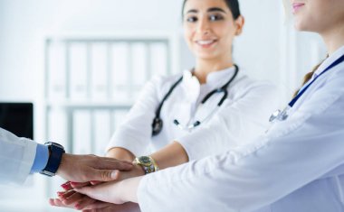 Doktorlar ve hemşireler tıbbi bir ekipte el ele tutuşuyorlar.