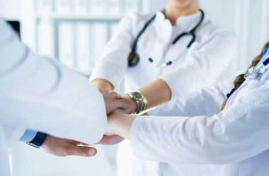 Doktorlar ve hemşireler tıbbi bir ekipte el ele tutuşuyorlar.