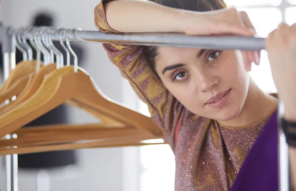 Mooie jonge stylist bij rek met hangers — Stockfoto