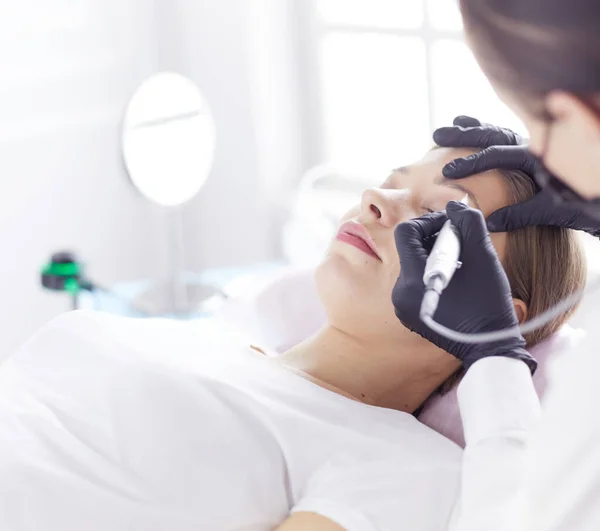 Jonge vrouw ondergaat procedure van wenkbrauw permanente make-up in schoonheidssalon — Stockfoto