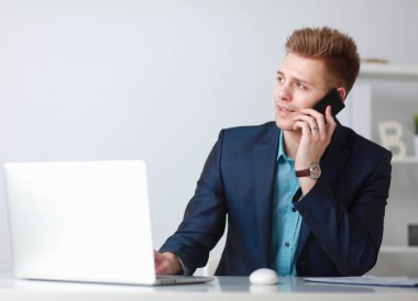 Yakışıklı genç adam dizüstü bilgisayarda oturuyor ve çalışıyor.