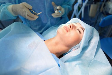 Ameliyat odasında arka planda erkek cerrah var.