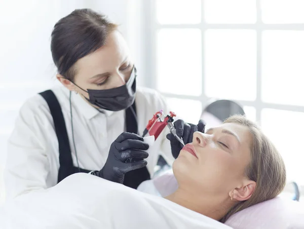 Cosmetoloog die permanente make-up op wenkbrauwen aanbrengt — Stockfoto