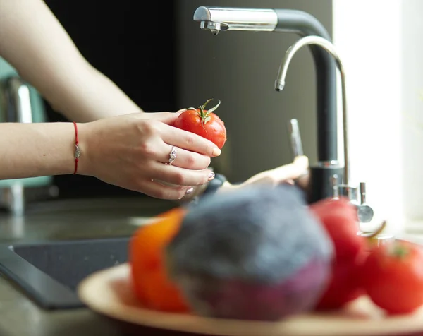 Frau wäscht Tomaten in Küchenspüle aus nächster Nähe — Stockfoto