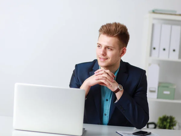 Przystojny młody człowiek siedzi i pracuje na laptopie — Zdjęcie stockowe