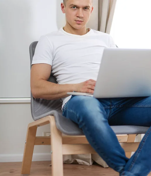 Handsome young man sitting and working on laptop computer — Stock Photo, Image