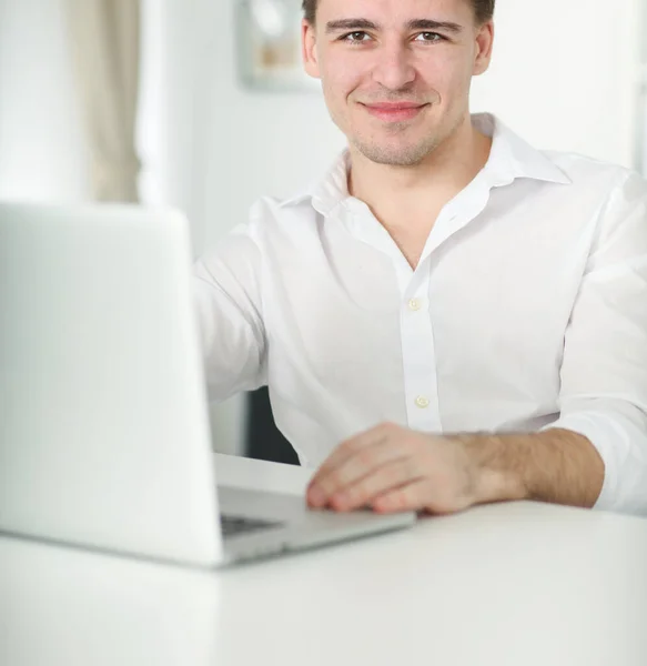 Guapo joven sentado y trabajando en el ordenador portátil — Foto de Stock