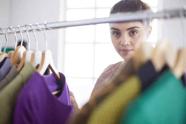 Mooie jonge stylist bij rek met hangers — Stockfoto