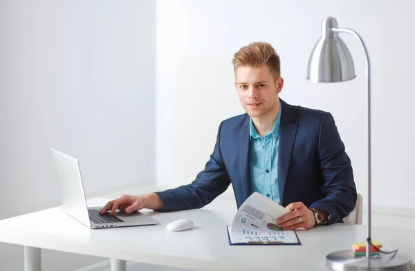 Bello giovane seduto e al lavoro sul computer portatile — Foto Stock