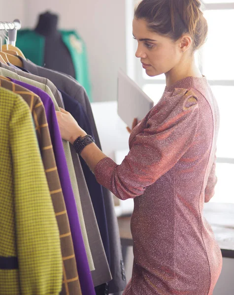 Mooie jonge stylist bij rek met hangers — Stockfoto