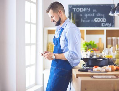 Mutfak arka planında poşet dolusu erzak tutan adam. Alışveriş ve sağlıklı gıda konsepti