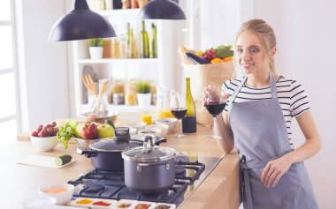 Güzel kadın mutfakta şarap içiyor.