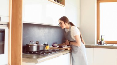 Mutfakta yemek yapmak için tablet bilgisayar kullanan genç bir kadın.