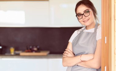 Mutfakta masanın yanında duran genç bir kadın.