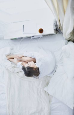 Sabahları yatakta otururken tablet kullanan ve kahve içen kadın portresi