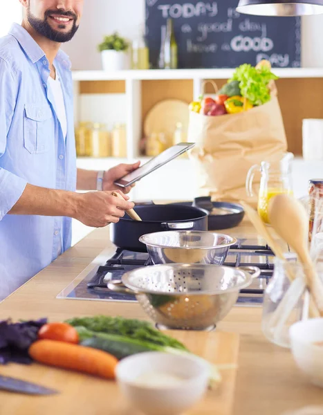 Man volgens recept op digitale tablet en lekker en gezond koken in de keuken thuis — Stockfoto