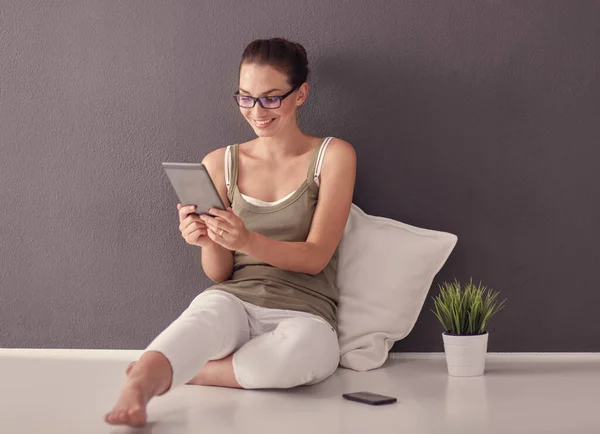 Bella giovane donna seduta sul pavimento con tablet — Foto Stock