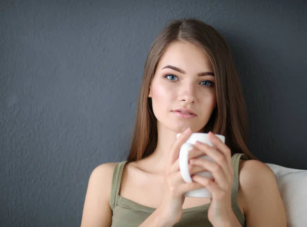 Hermosa mujer relajándose en un sofá blanco con una taza de café — Foto de Stock