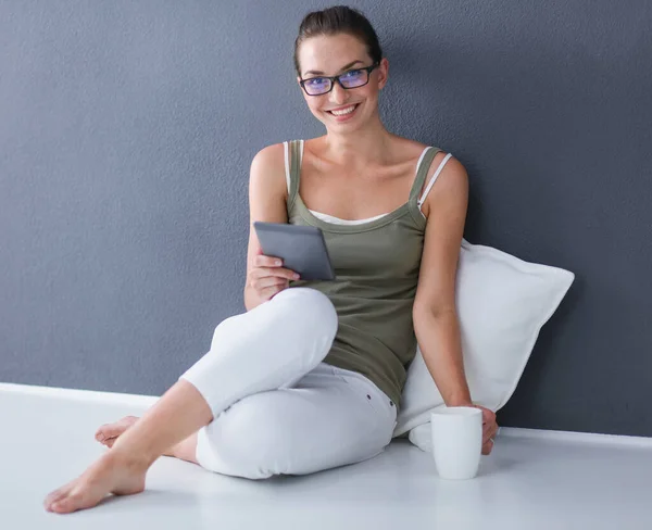 Krásná mladá žena sedí na podlaze s tabletem — Stock fotografie