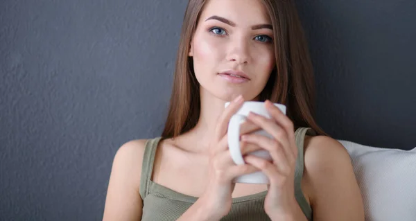 Hermosa mujer relajándose en un sofá blanco con una taza de café —  Fotos de Stock