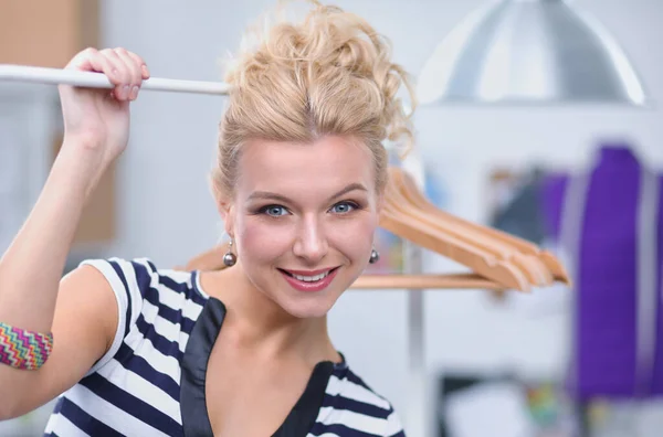 Mooie jonge stylist bij rek met hangers — Stockfoto